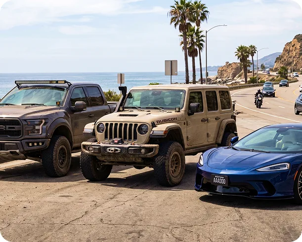 Lifted truck, Jeep Wrangler, and McLaren parked together at a coastal overlook